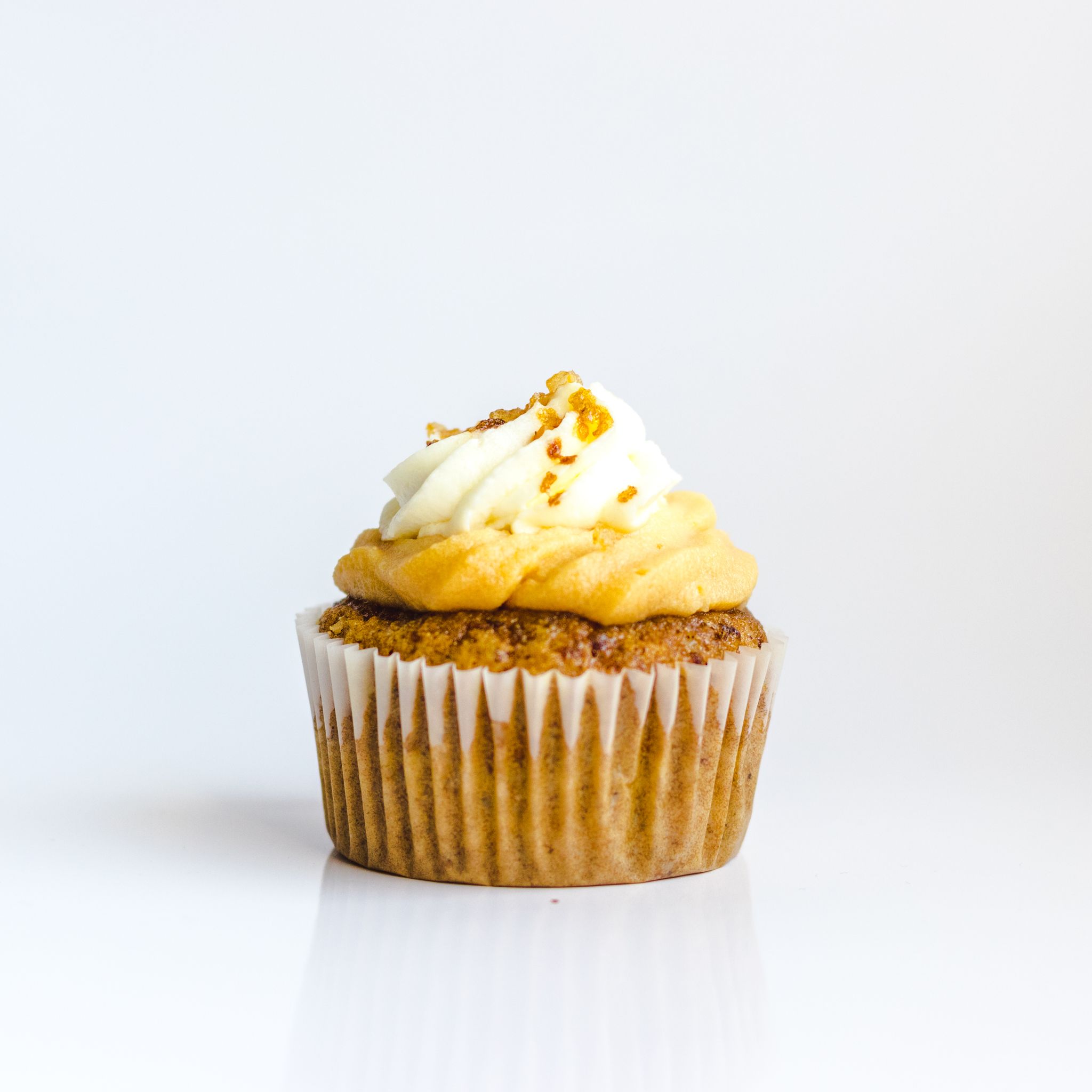 A delectable cupcake with creamy frosting on a white background, perfect for food photography.